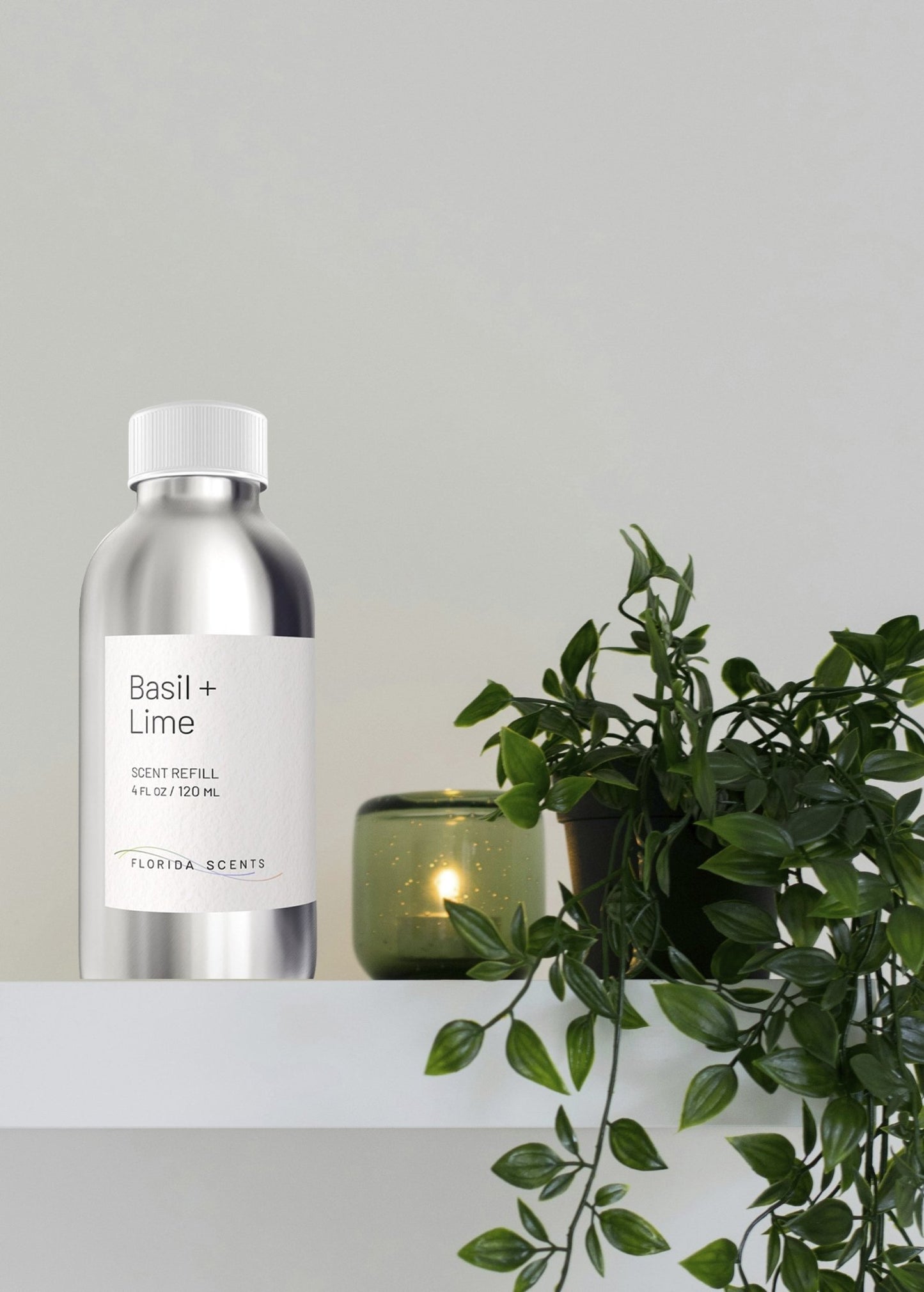 Basil & Lime Scent Refill - Florida Scents Essentials bottle on a white shelf beside a green plant and candle. Ideal for a vibrant, focused atmosphere.