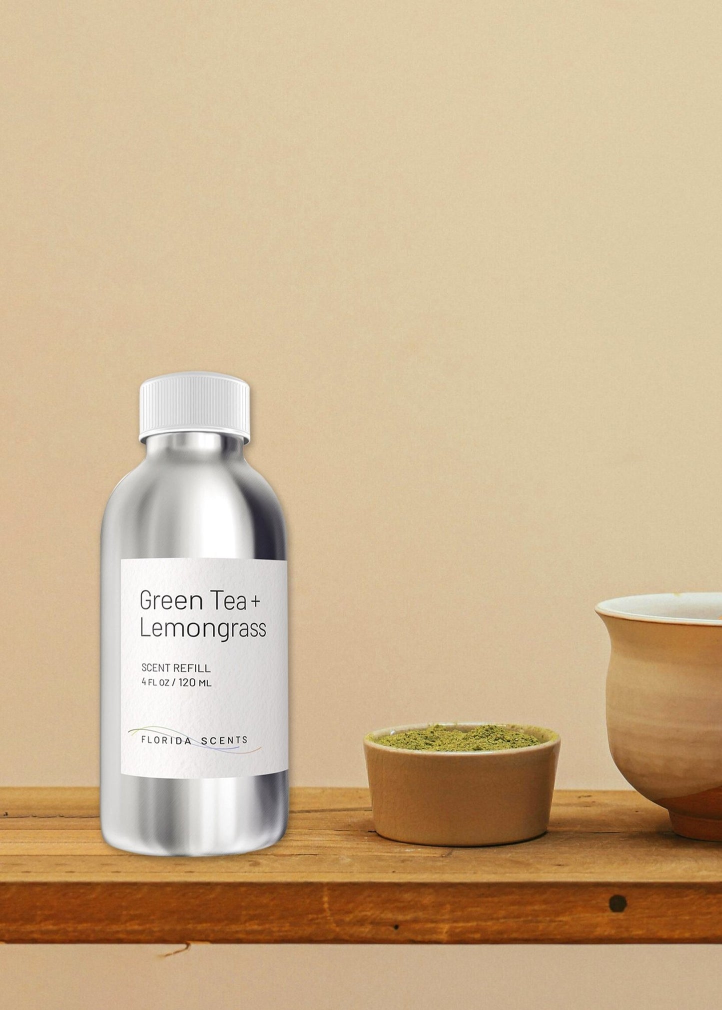 Green Tea & Lemongrass Scent Refill by Florida Scents Essentials in a sleek silver bottle, placed on a wooden shelf beside a tea cup. Ideal for home or office use.