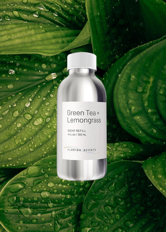 Green Tea & Lemongrass Scent Refill by Florida Scents Essentials, 4 fl oz bottle placed on dewy green leaves. Ideal for home or office use.